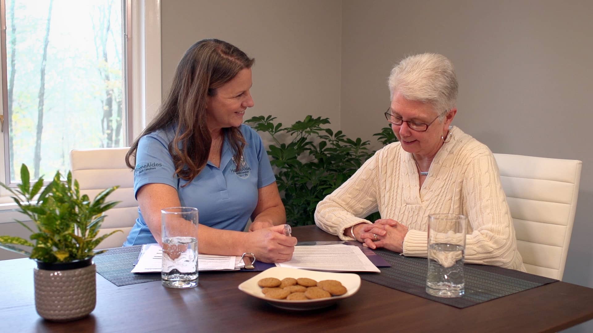 Picture of a caregiver sitting with a client explaining information about home care services